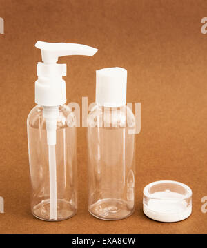 Empty travel cosmetics bottles on the brown background. Stock Photo