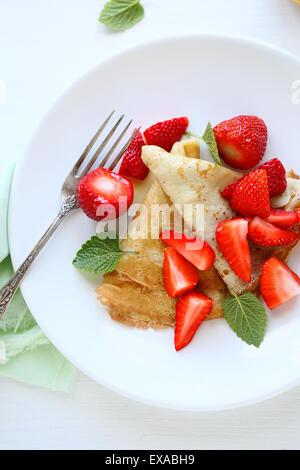 crepes with slices of strawberries on plate