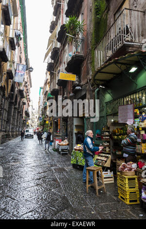 Shopkeeper and customer in wet narrow street, Historic Centre (Centro Storico), UNESCO Site, Naples, Campania, Italy Stock Photo