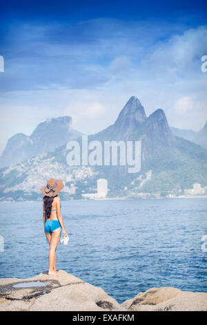 A 20-25 year old young Brazilian woman standing on the Arpoador rocks, Rio de Janeiro, Brazil Stock Photo