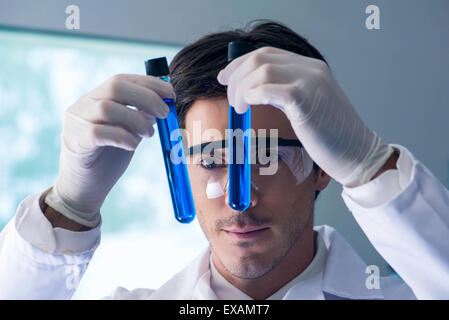Researcher scrutinizing test tubes containing blue liquid in lab Stock Photo