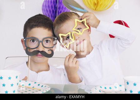Boys wearing funny disguises at birthday party Stock Photo