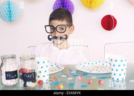 Boy wearing fake glasses and mustache at a birthday party Stock Photo