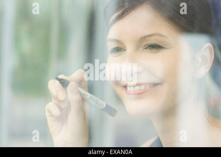 Woman preparing to write on window with marker Stock Photo