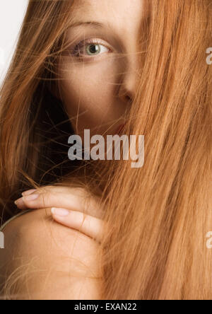Woman with red hair covering half of face, hand on shoulder, portrait Stock Photo