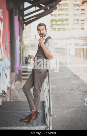 handsome big moustache hipster man smoking pipe in the city Stock Photo