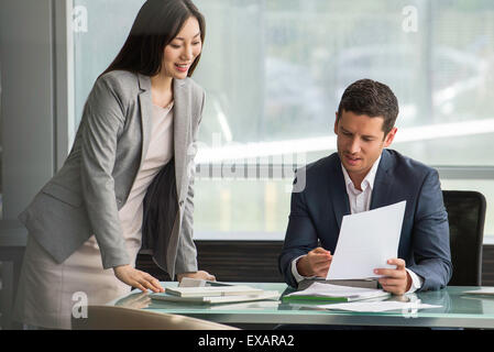 Executive reviewing document with assistant Stock Photo