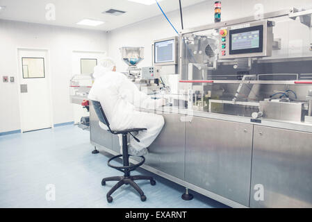 Worker operating industrial pill packing machinery Stock Photo