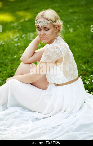 Woman sits in the white dress on meadow Stock Photo