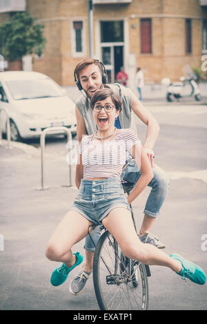 couple of friends young  man and woman riding bike in the city Stock Photo