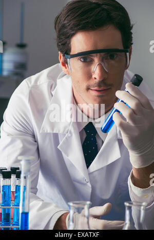 Scientist holding test tube in lab, looking at camera with determined expression Stock Photo