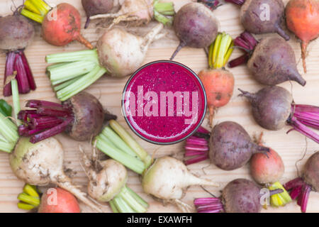 Beta vulgaris. Beetroot smoothie drink surrounded by harvested red, yellow and white beetroots Stock Photo