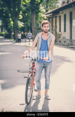 young hipster gay man with bike in the city Stock Photo
