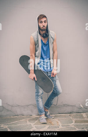 young hipster gay man with skate in the city Stock Photo
