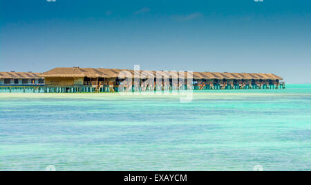 Water bungalows of an island resort extend into the lagoon in Maldives Stock Photo