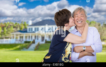 Attractive Affectionate Senior Chinese Couple In Front of Beautiful House. Stock Photo