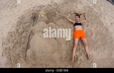 Smiling sandy snowman on the sea beach. Stock Photo