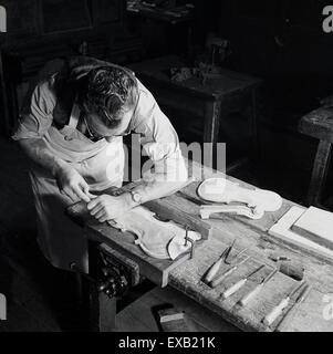 1950s, historical, adult male craftsman at his bench making the front and back of a violin Stock Photo