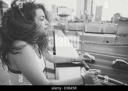 young beautiful long curly hair hipster woman listening to music with tablet in the city Stock Photo