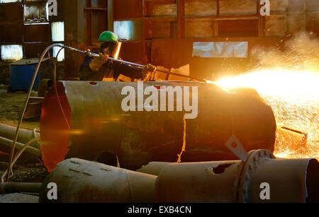 worker using torch cutter inside of plant Stock Photo