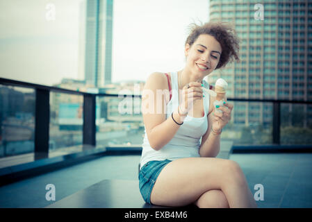 young beautiful long curly hair hipster woman eating ice cream in the city Stock Photo