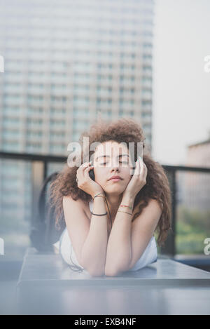 young beautiful long curly hair hipster woman listening to music with tablet in the city Stock Photo