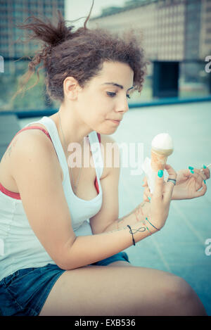 young beautiful long curly hair hipster woman eating ice cream in the city Stock Photo
