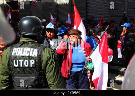 La Paz, Bolivia, 10th July 2015. A protestor from the Potosi area confronts riot police during a protest by the Potosi Civic Committee and supporters. The protestors are in La Paz to demand the government keeps electoral promises made to the region in the past. The red and white flags are the flags of Potosí Department. Credit:  James Brunker / Alamy Live News Stock Photo