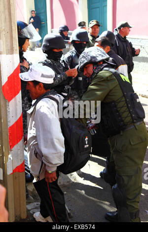 La Paz, Bolivia, 10th July 2015. A riot policeman searches the bag of a passer by before he enters Plaza Murillo (where the Presidential Palace and Congress buildings are) during a protest by the Potosi Civic Committee and supporters. The protesters are in La Paz to demand the government keeps electoral promises made to the region in the past. Credit:  James Brunker / Alamy Live News Stock Photo