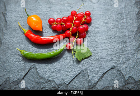 Redcurrants and chillies on slate platter. Stock Photo