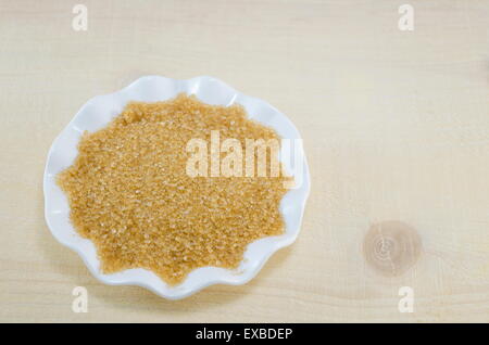 Brown sugar in a white plate on a wooden table Stock Photo