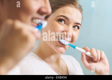 Young couple living together, washing teeth in bathroom in the morning. The woman looks happily at her boyfriend. Concept of new Stock Photo