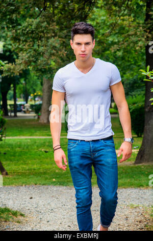 Serious Man Is Walking In Jeans And White T Shirt And Looking Away Front Side View Full Length Studio Shot Isolated On White Stock Photo Alamy