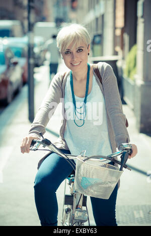 beautiful young blonde short hair hipster woman witk bike in the city Stock Photo