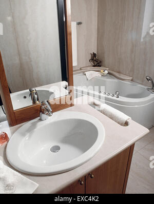 foreground of washbasin overlooking on the bathtub in the modern bathroom whose wall and floor are coated with marble Stock Photo