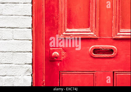 A vibrant red painted wooden front door with a letterbox Stock Photo