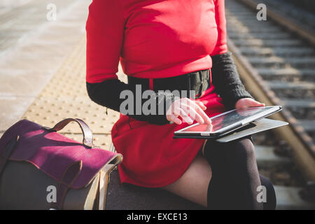 close up hands woman using tablet at the station waiting for train Stock Photo