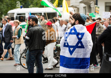 Berlin, Germany. 11th July, 2015. A man wearing an Israeli flag and a kippah watches a Pro-Palestinian rally in Berlin, Germany, 11 July 2015. Anti-Israeli rallies are held in Iran on Quds Day. Photo: GREGOR FISCHER/dpa/Alamy Live News Stock Photo