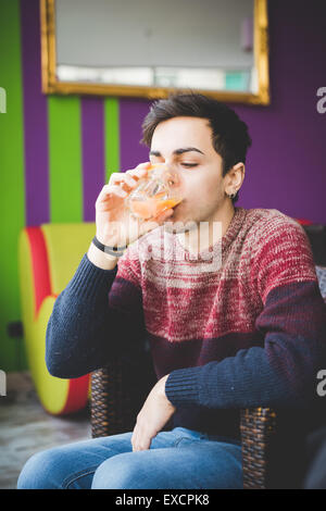 young handsome man sitting at the bar drinking orange juice Stock Photo