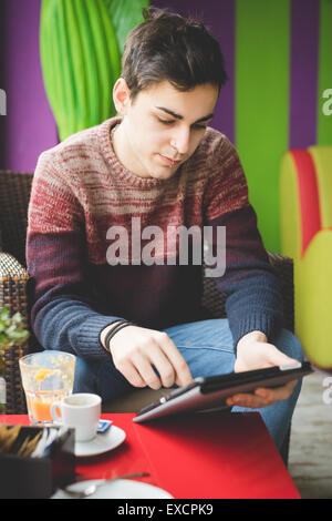 young handsome man sitting at the bar using tablet connected wireless online Stock Photo