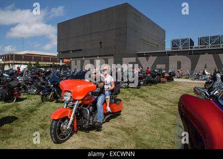 A couple ride a custom red motorcycle at the Harley-Davidson Museum in Milwaukee, Wisconsin during a bike rally. Stock Photo