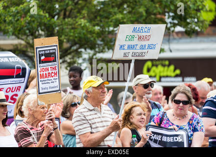 Henley-on-Thames, UK. 11th July, 2015. An elderly man and woman, protesters taking part in a demonstration, carry placards for the 'Save Our Beds' campaign in a peaceful protest march in Henley-on-Thames, Oxfordshire, England, on Saturday 11 July 2015 against the Oxfordshire Clinical Commissioning Group's plans for its new health campus, Townlands Hospital.  The new hospital was originally planned to have 18 beds, now changed to 5 beds in a care home to be built next to the hospital, which would leave Townlands without any beds for 6 months. Credit:  Graham Prentice/Alamy Live News Stock Photo