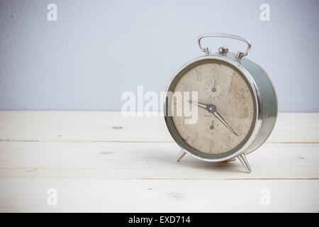Old alarm clock on wooden table,  vintage tone Stock Photo