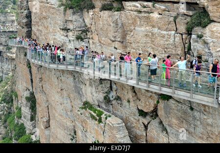 Baoding, China's Hebei Province. 12th July, 2015. Tourists walk on a pavement built with glass on the cliff at Baishishan scenic spot in Laiyuan, north China's Hebei Province, July 12, 2015. The glass pavement, 95-meter-long, has an altitude of 1,900 meters. Credit:  Mou Yu/Xinhua/Alamy Live News Stock Photo