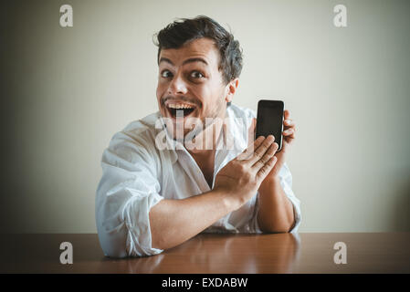 young stylish man with white shirt on the phone behind a table Stock Photo