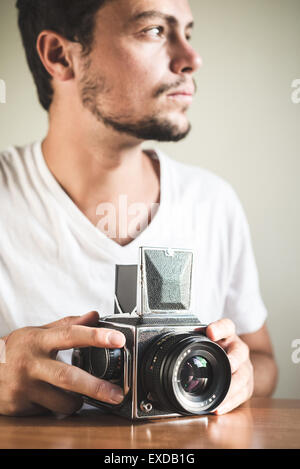 young stylish hipster man with old camera on the table at home Stock Photo