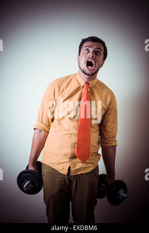 funny crazy young man weightlifting on gray background Stock Photo
