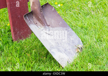 A Red Spade Standing on Green Grass Stock Photo