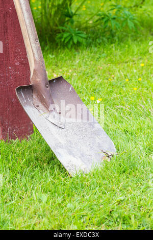A Red Spade Standing on Green Grass Stock Photo