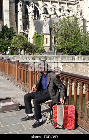 Accordion player at Pont au double, Notre-Dame Cathedral in fourth arrondissement, Ile de la Cite, Paris. France. Stock Photo